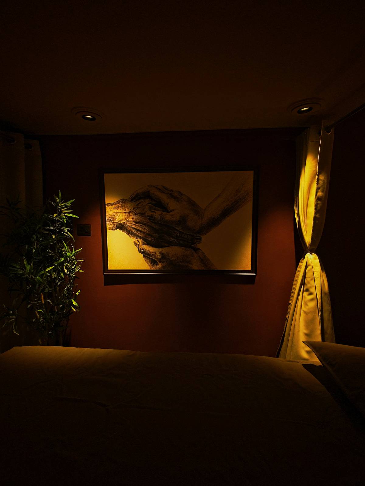 Sereñyā treatment room — healing hands artwork on amber wall